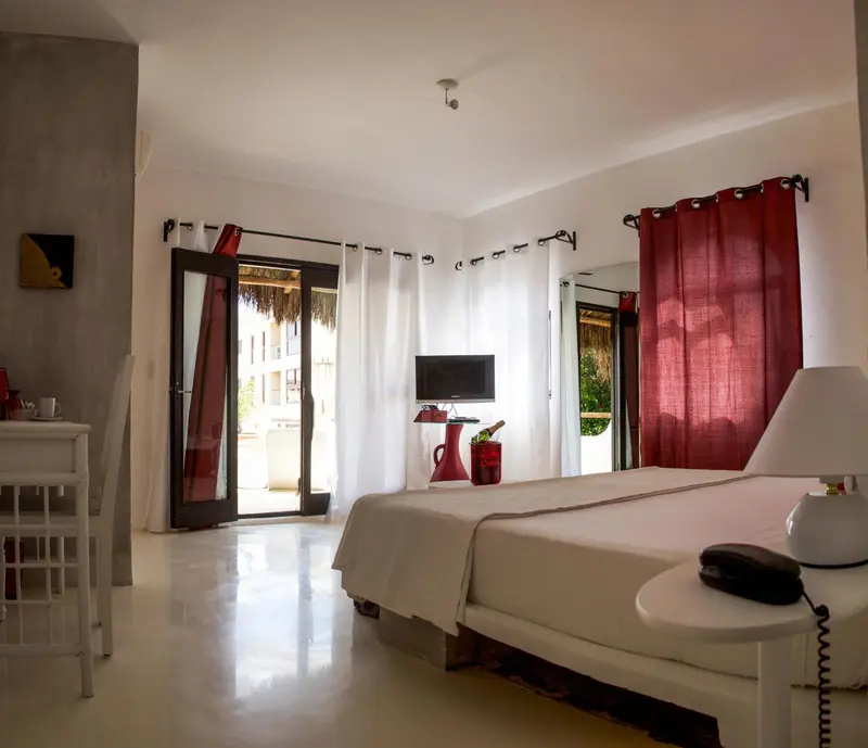 Une chambre lumineuse avec un lit blanc et un accès à une terrasse.
