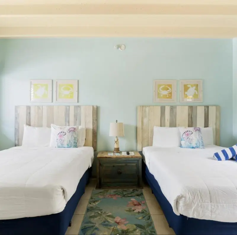 Deux lits simples dans une chambre décorée de couleurs pastel et d'illustrations marines.