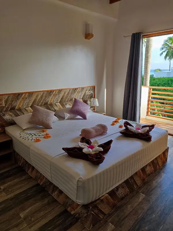 Une chambre avec un lit double décoré de fleurs et de serviettes en forme d'animaux, donnant sur une vue extérieure.