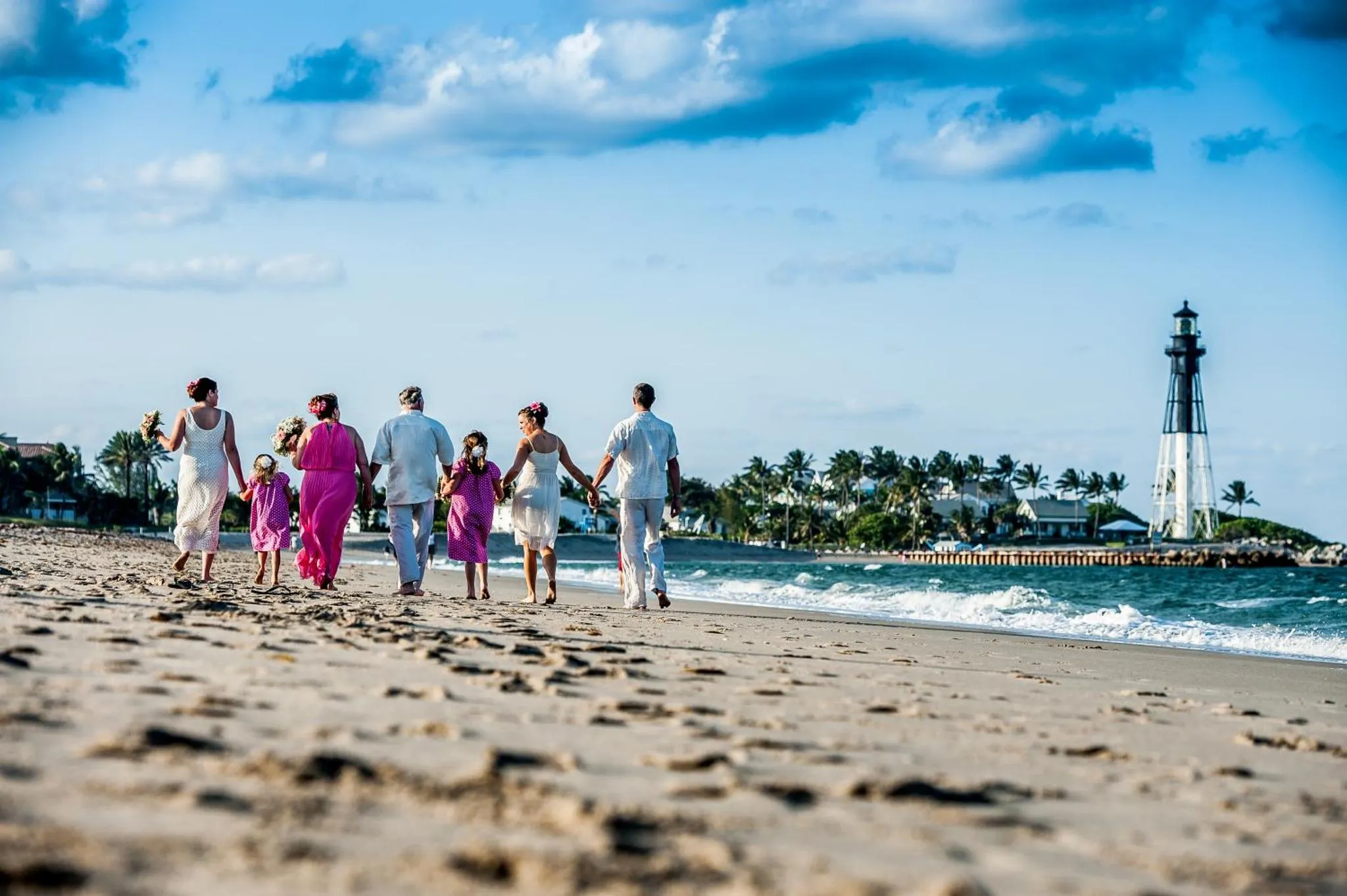 Groupe de personnes marchant sur une plage de sable fin vers la mer.