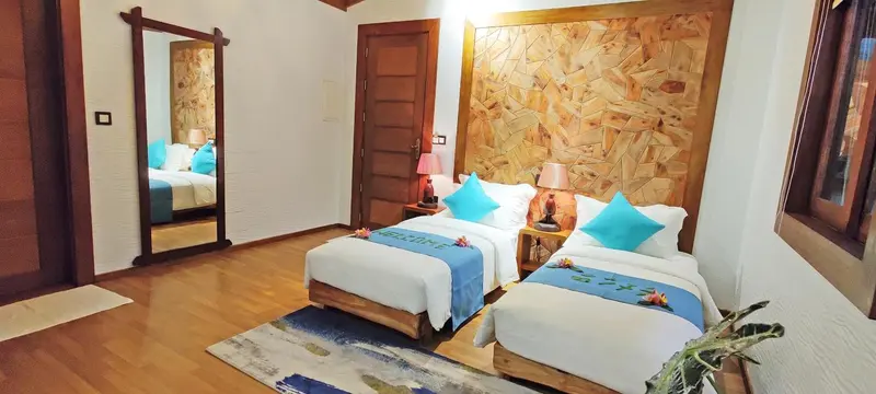Chambre lumineuse avec deux lits simples et décoration florale.