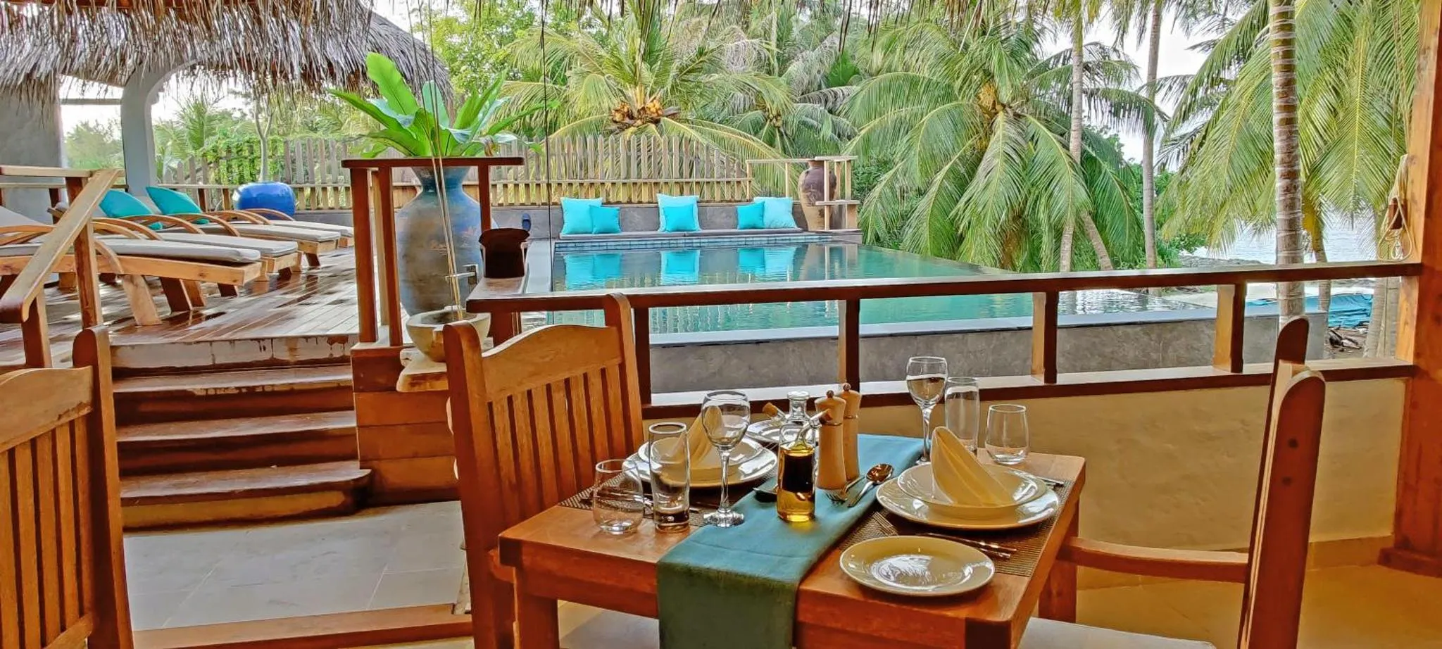 Une table est dressée avec de la vaisselle et des verres sur une terrasse en bois.
