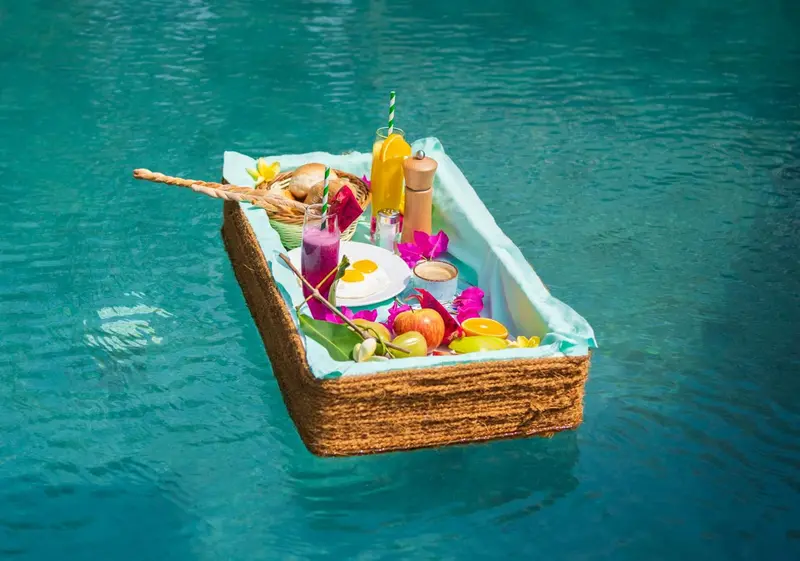 Un plateau de petit-déjeuner flottant dans une piscine turquoise.