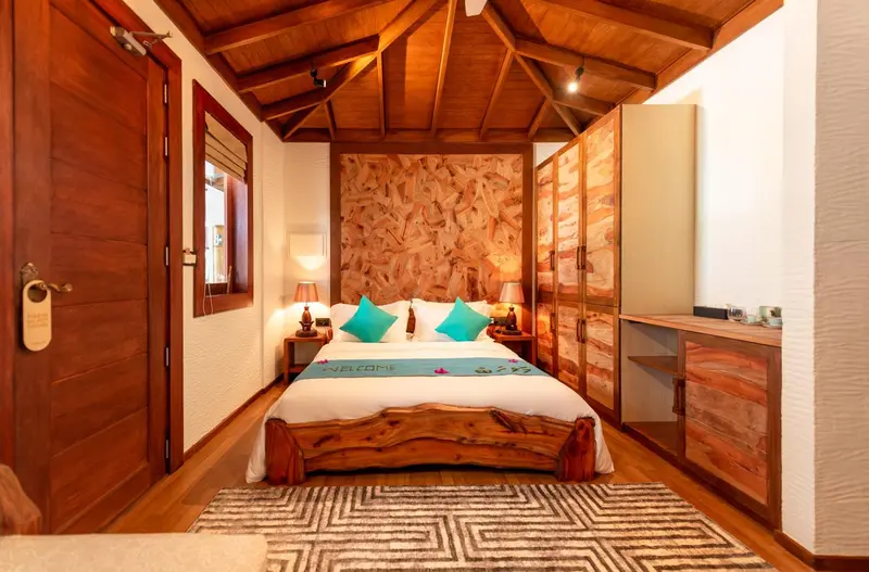 Une chambre lumineuse avec un lit recouvert d'une courtepointe turquoise et un mur en pierre.