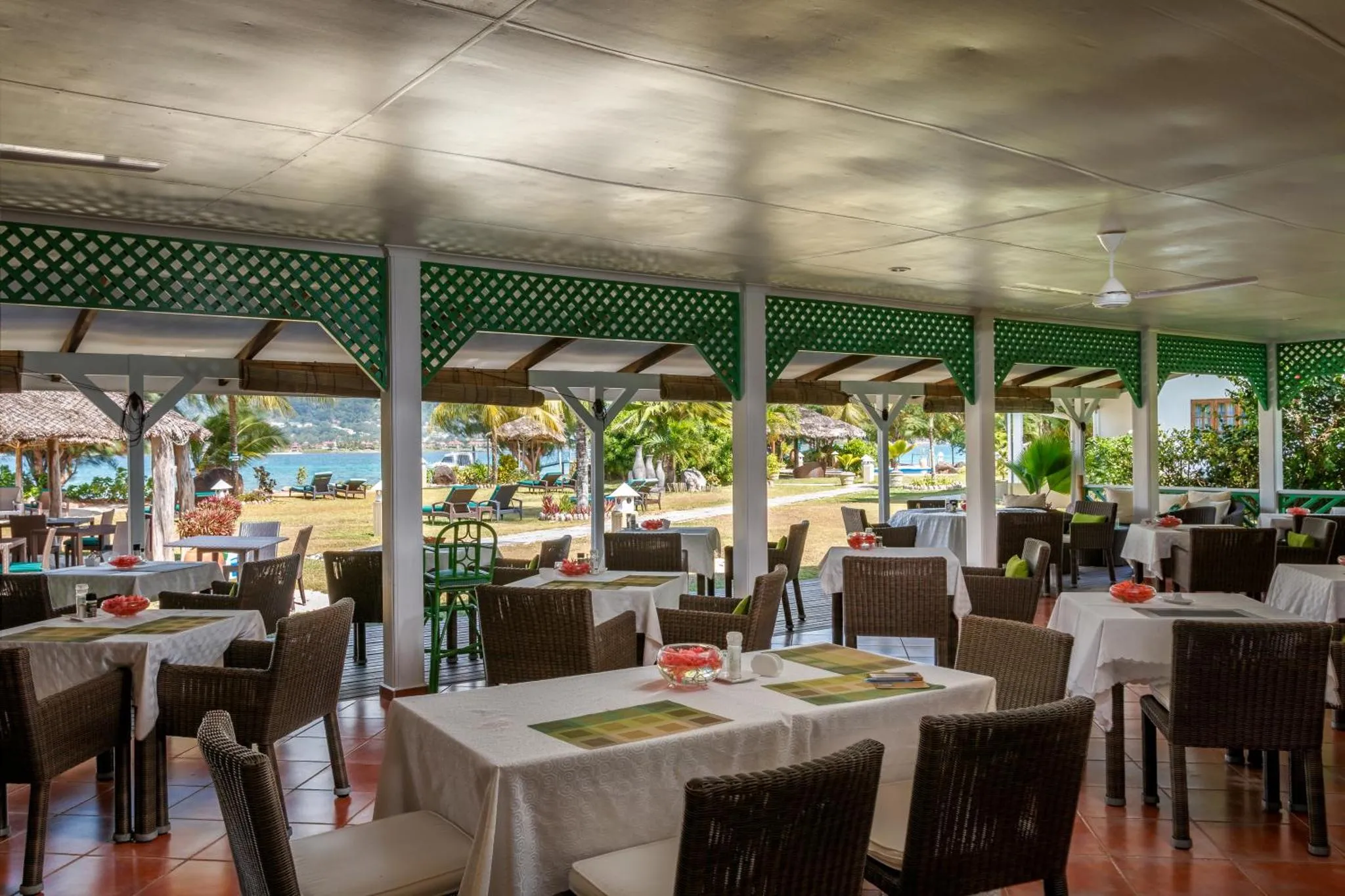 Une salle à manger extérieure avec des tables nappées et des chaises en osier.