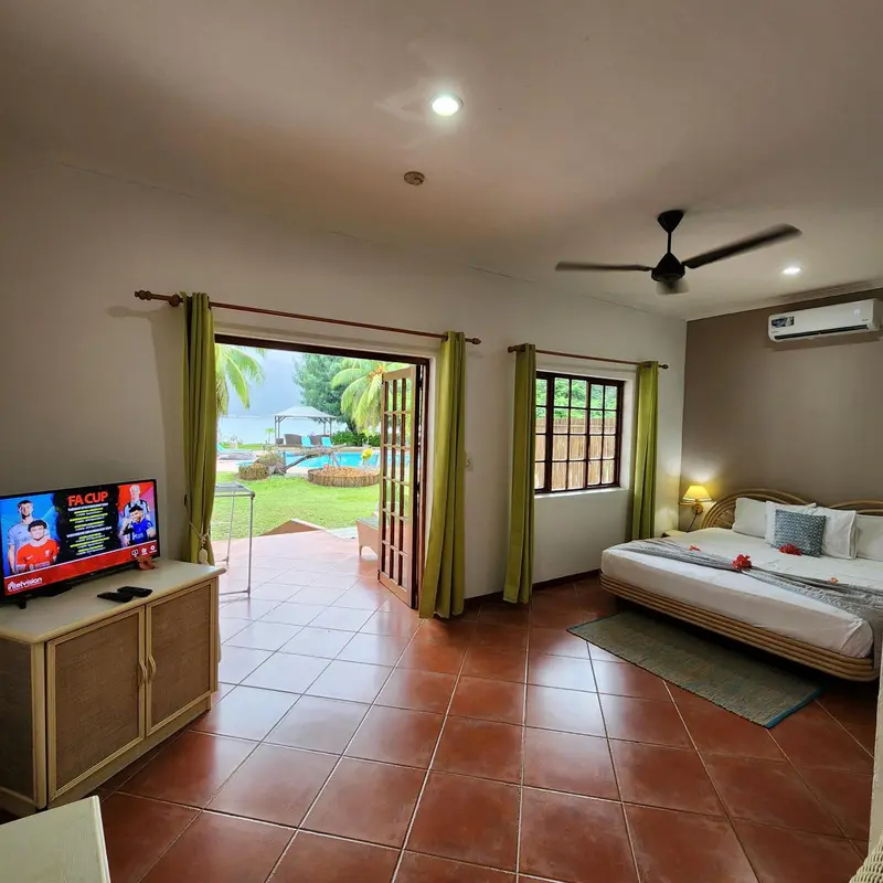 Chambre lumineuse avec lit double et vue sur un jardin tropical.