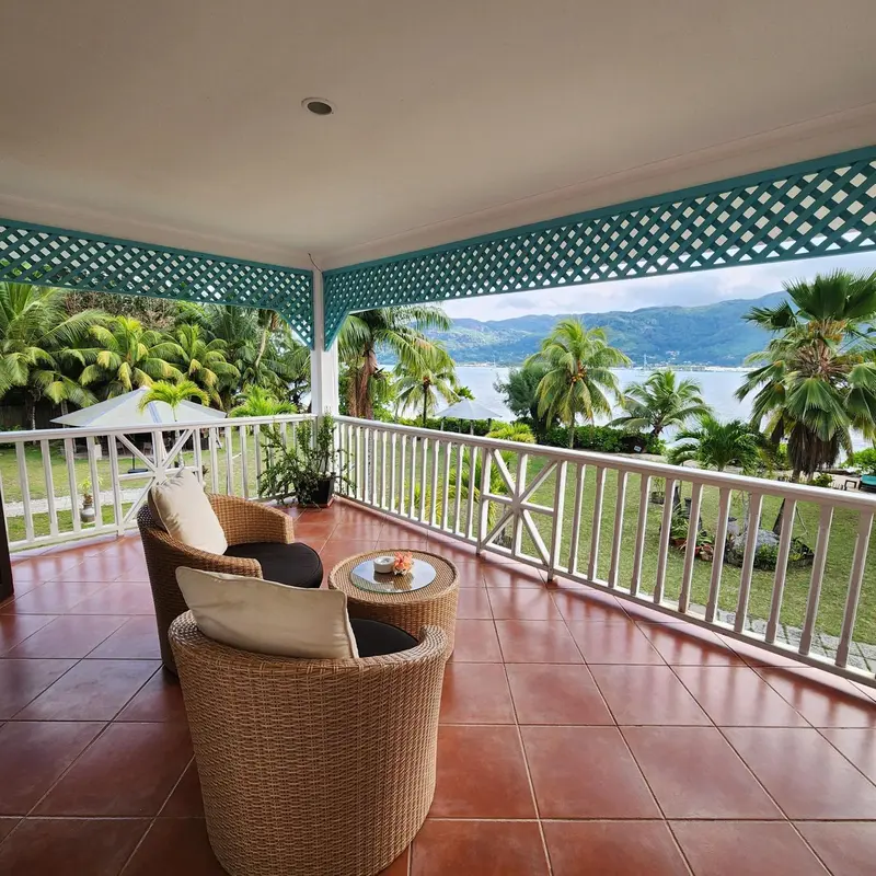 Terrasse carrelée avec mobilier en rotin et vue sur la mer.