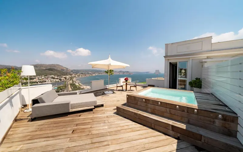 Terrasse aménagée avec salon de jardin et jacuzzi offrant une vue sur la mer.