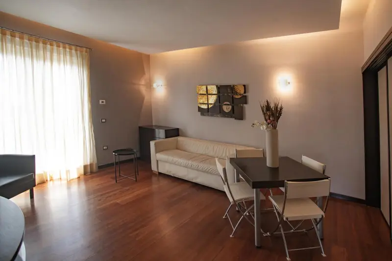 Un salon lumineux avec un canapé blanc et une table à manger en bois.