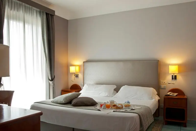 Une chambre lumineuse avec un grand lit et une table de chevet.