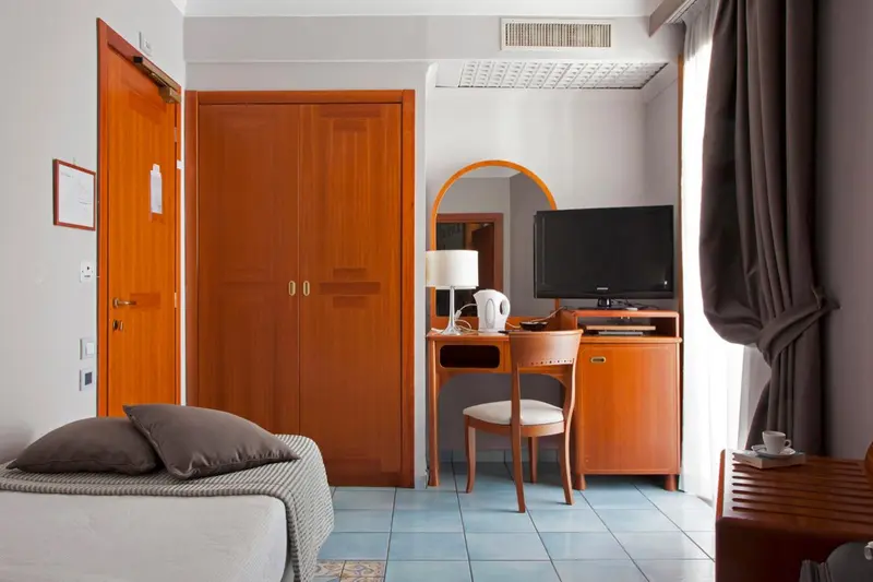 Une chambre d'hôtel lumineuse avec un bureau et un téléviseur.