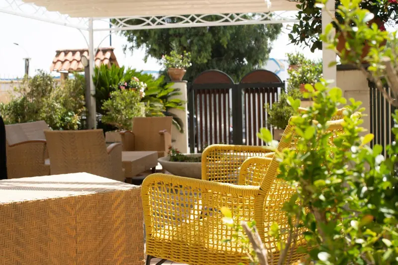 Espace de détente extérieur avec mobilier en osier et végétation luxuriante.