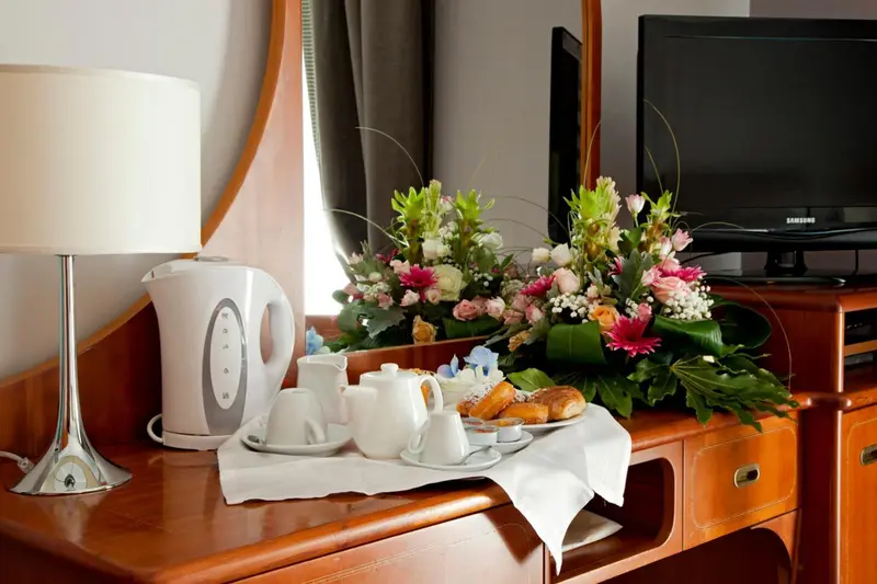 Une table de chevet en bois présente une bouilloire, une tasse de thé et des pâtisseries.