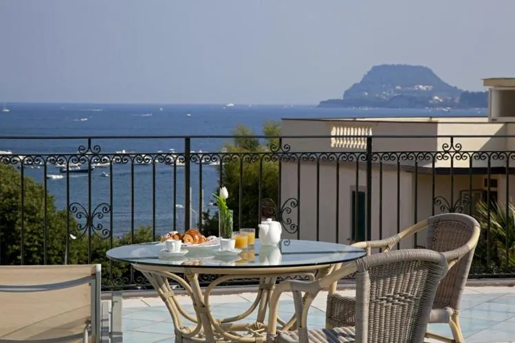 Une table ronde avec un petit-déjeuner est mise en scène sur une terrasse avec vue sur la mer.