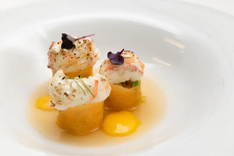 Assiette raffinée présentant des bouchées de fruits de mer et une sauce crémeuse.
