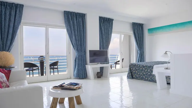 Une chambre lumineuse s'ouvre sur une vue mer par de grandes baies vitrées.