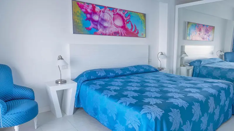 Chambre lumineuse avec un grand lit recouvert d'une couverture à motifs.