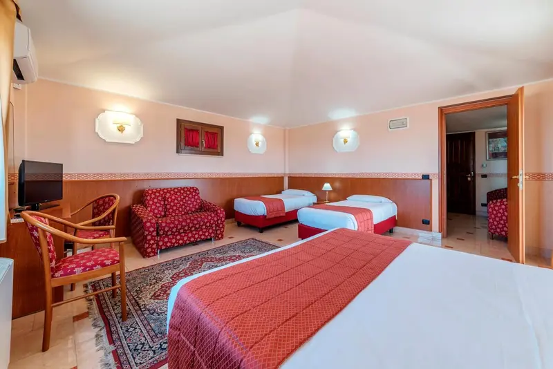 Chambre lumineuse avec deux lits simples et un canapé rouge.