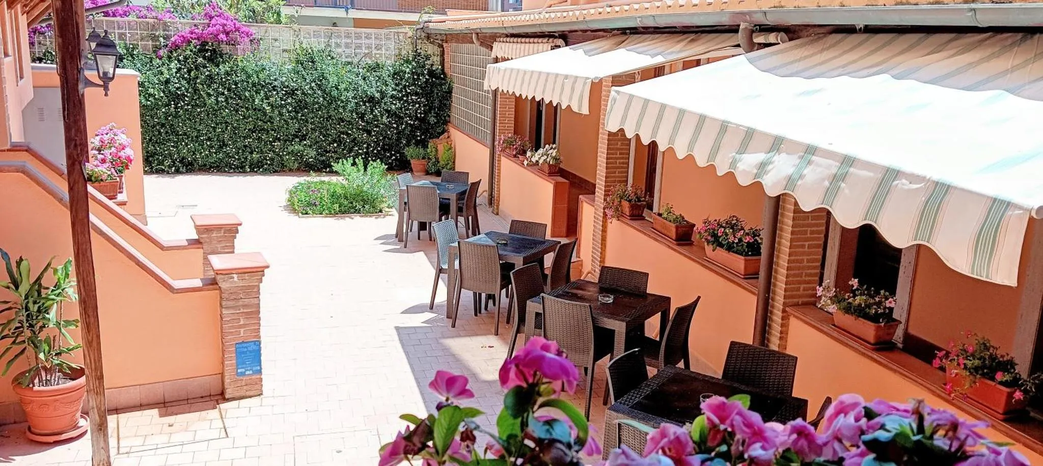 Terrasse ombragée avec tables et chaises en plastique.