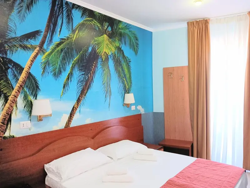 Une chambre avec un lit et un grand décor mural représentant des palmiers.