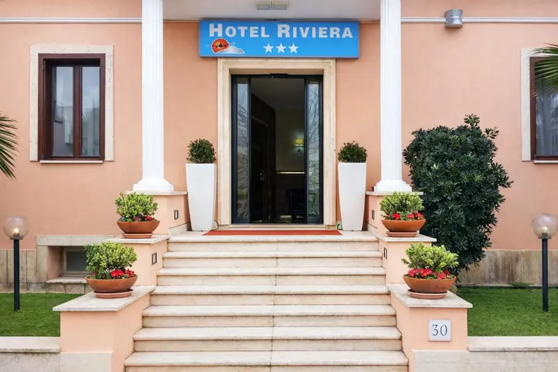 Façade d'un bâtiment rose avec l'entrée d'un hôtel et des jardinières.