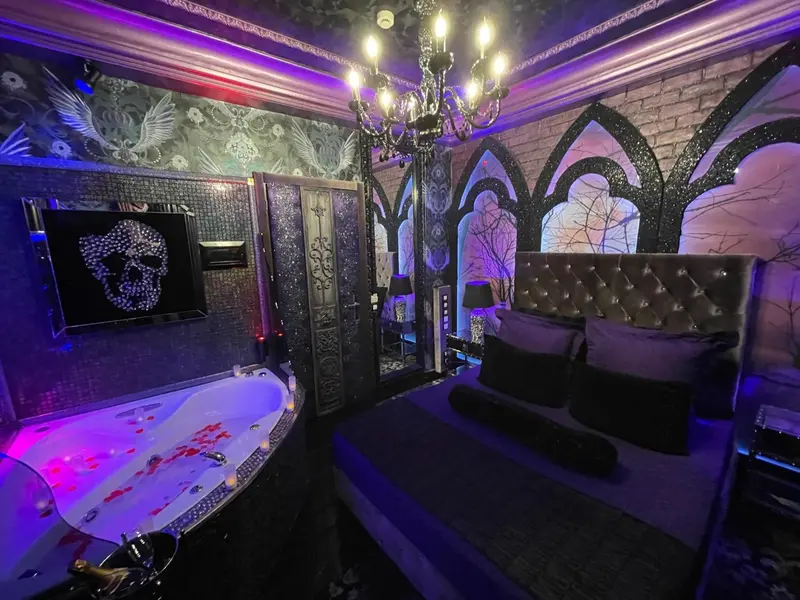 Une chambre décorée dans un style gothique avec un jacuzzi rempli de pétales.