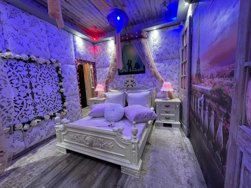 Une chambre à coucher décorée dans des tons violets et blancs avec un lit à baldaquin.