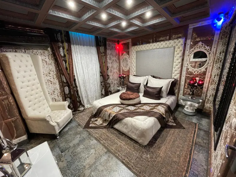 Chambre à coucher luxueuse avec un grand lit et un fauteuil haut.