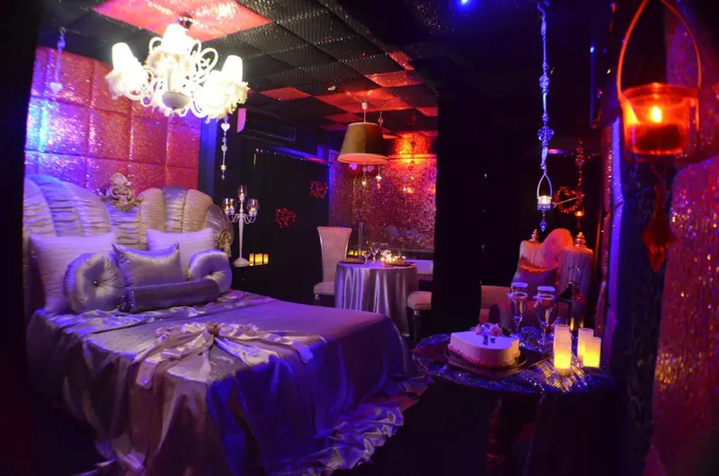 Une chambre luxueuse est illuminée par des lumières colorées et décorée de tissus chatoyants.