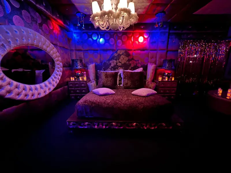 Une chambre à coucher luxueuse avec un lit à baldaquin et un éclairage coloré.