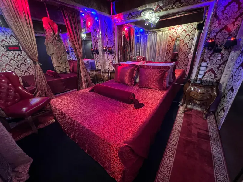 Une chambre à coucher décorée de rideaux rouges et de motifs floraux.