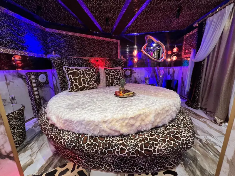 Une chambre à coucher avec un grand lit rond décoré de fausse fourrure et de motifs animaliers.