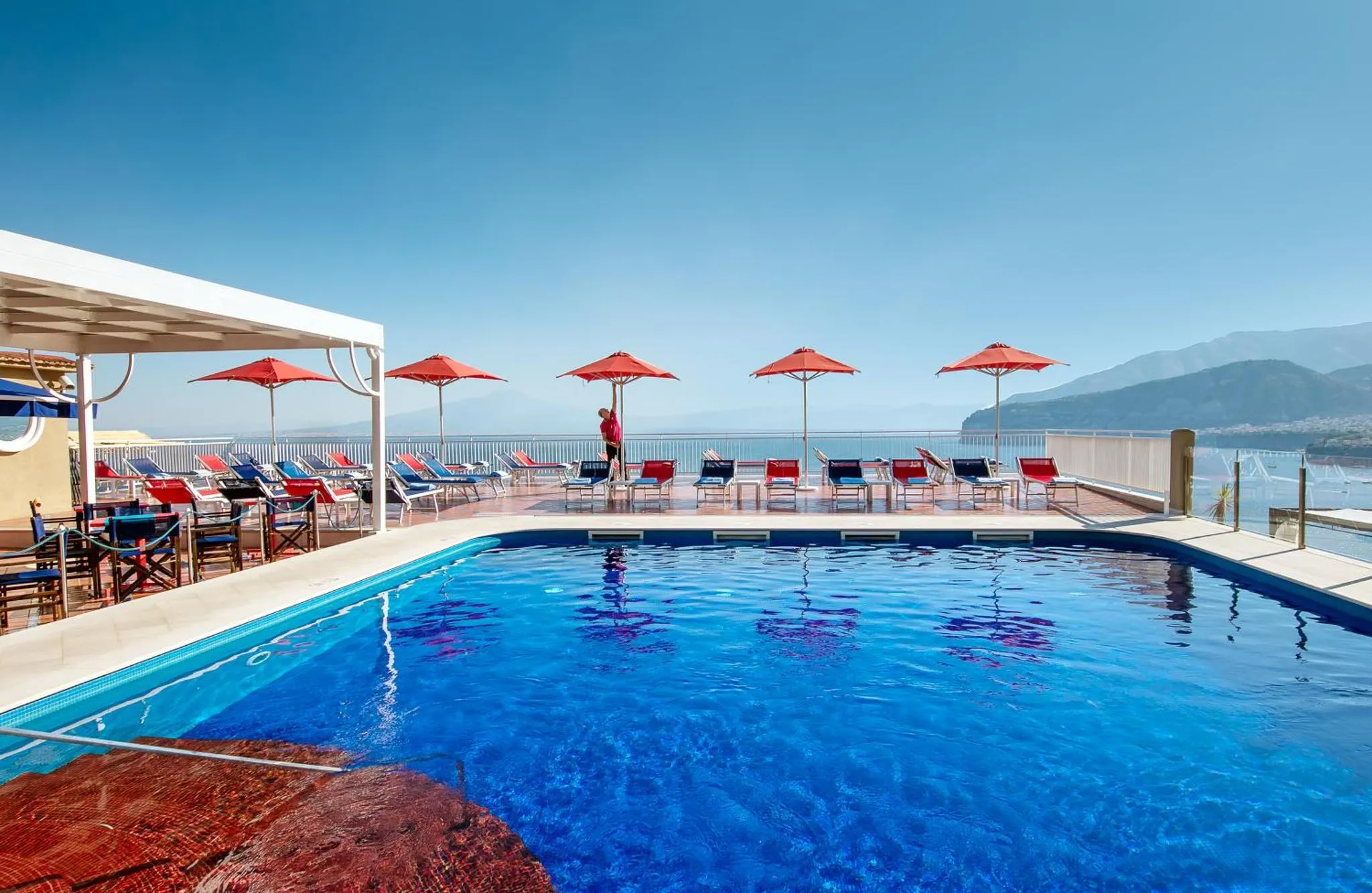 Terrasse avec piscine et chaises longues face à la mer.