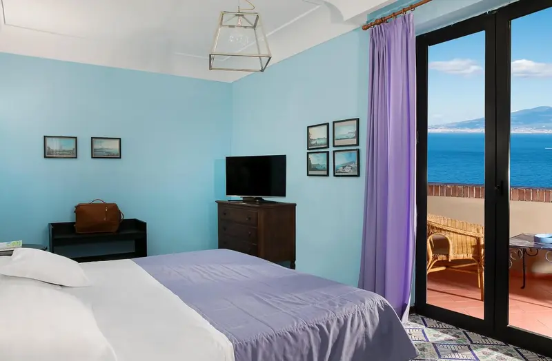 Chambre lumineuse avec un lit blanc et une vue sur la mer.