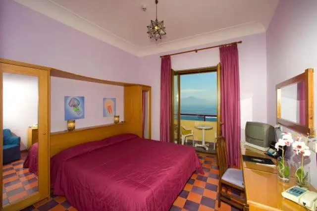 Chambre avec un grand lit et une vue sur la mer par une baie vitrée.