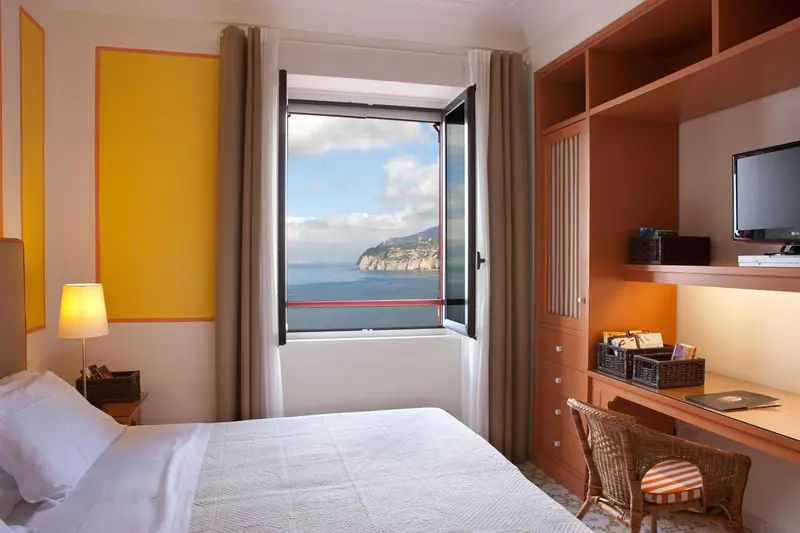 Une chambre lumineuse avec un lit blanc et une vue sur la mer.