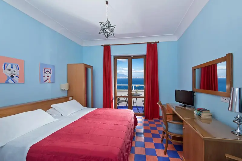Chambre lumineuse avec un lit double et une vue sur la mer.
