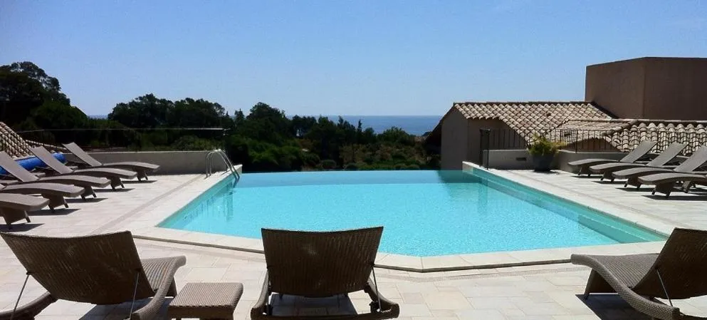 Transats et piscine au bord d'une terrasse ensoleillée avec vue sur la mer.