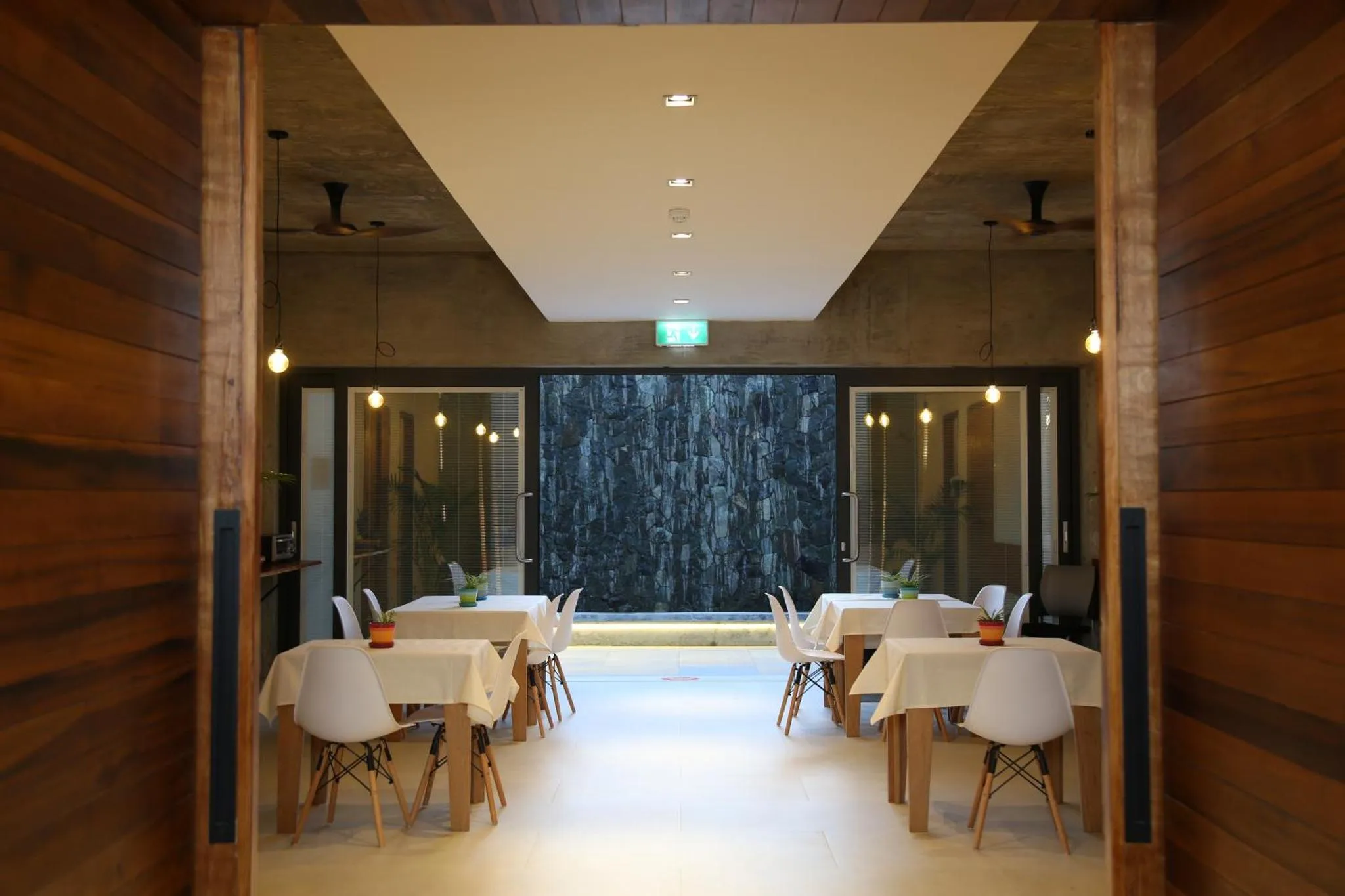 Une salle lumineuse avec des tables nappées et des chaises en bois.