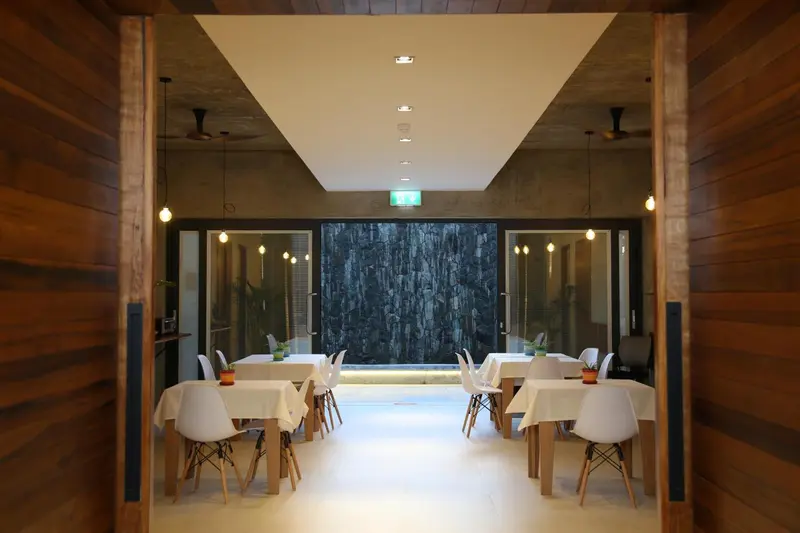 Une salle lumineuse avec des tables nappées et des chaises en bois.