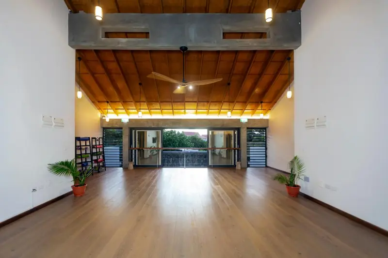 Vaste salle lumineuse avec plancher en bois et plafond en lambris.