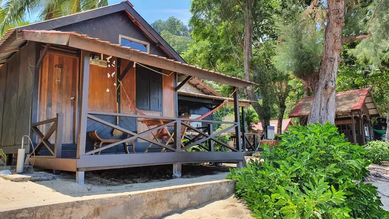Petite maison en bois sur pilotis avec une terrasse ombragée.