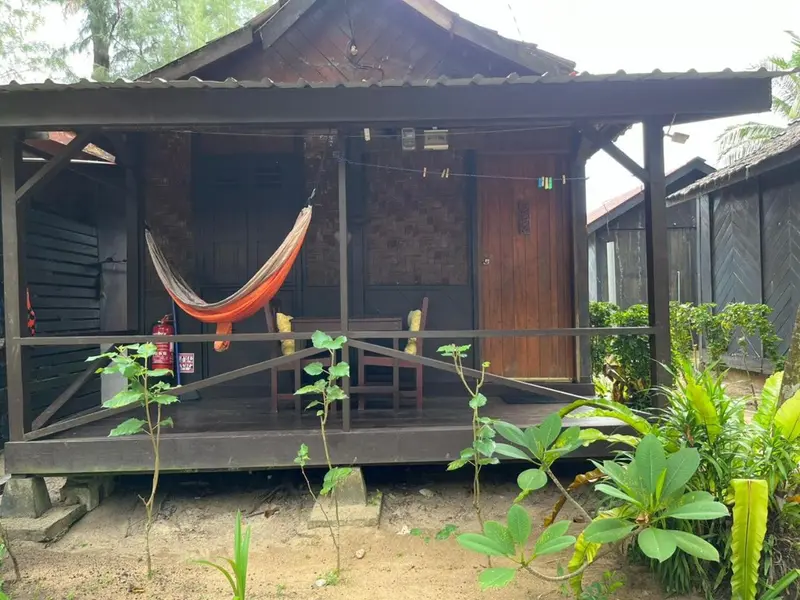 Une petite maison en bois avec une terrasse et un hamac.