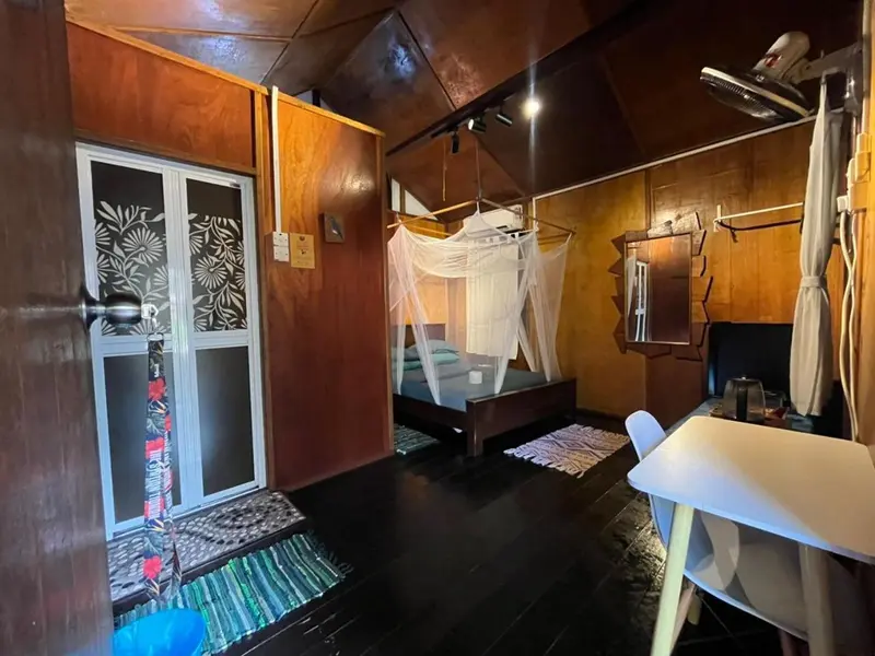 Une chambre rustique avec un lit à moustiquaire et une petite table.