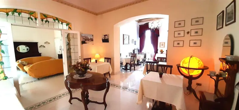 Une salle lumineuse avec des tables dressées et un coin salon.