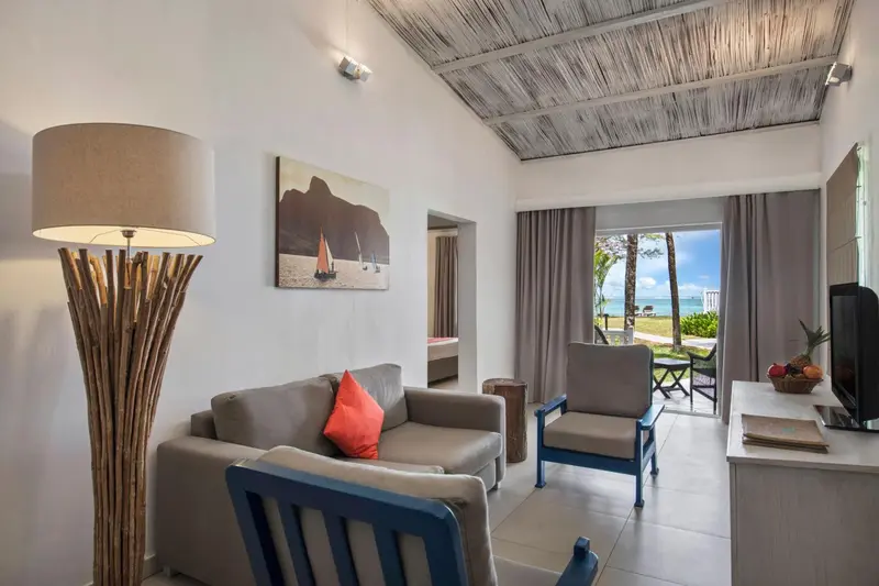 Un salon lumineux avec canapé, fauteuils et vue sur la mer.