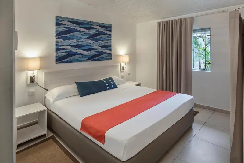 Une chambre lumineuse avec un grand lit recouvert d'une courtepointe colorée.