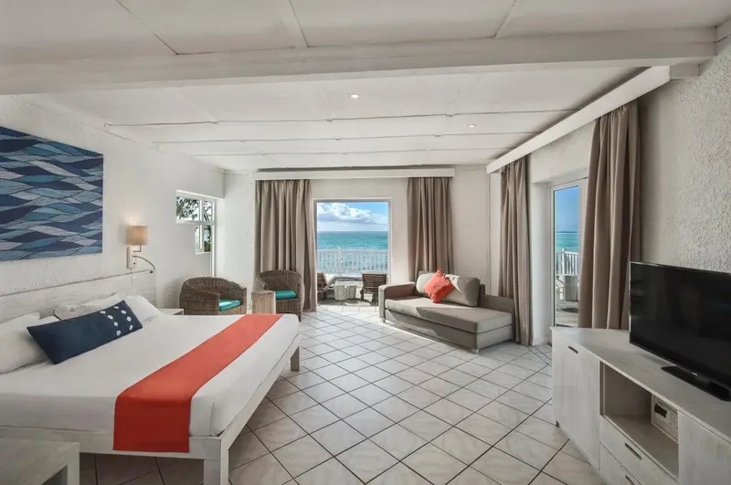 Espace de vie lumineux avec lit et canapé face à la mer.