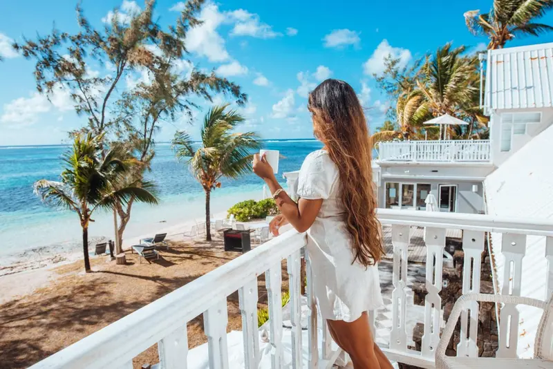 Une femme se tient sur une terrasse en admirant la mer.