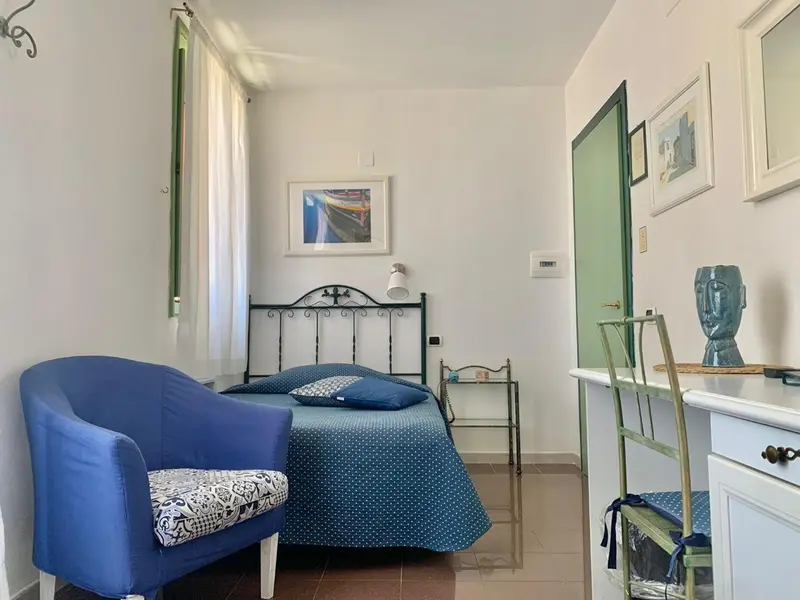 Une chambre lumineuse avec un lit et un fauteuil.